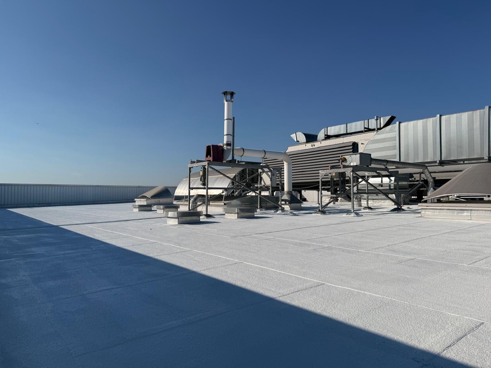Reflective roof of the Dugny site under a blue sky, flues and equipment