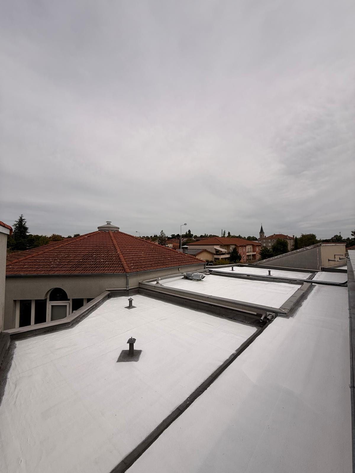 Treated school roof among the tiled roofs of Saint-Laurent-d’Agny