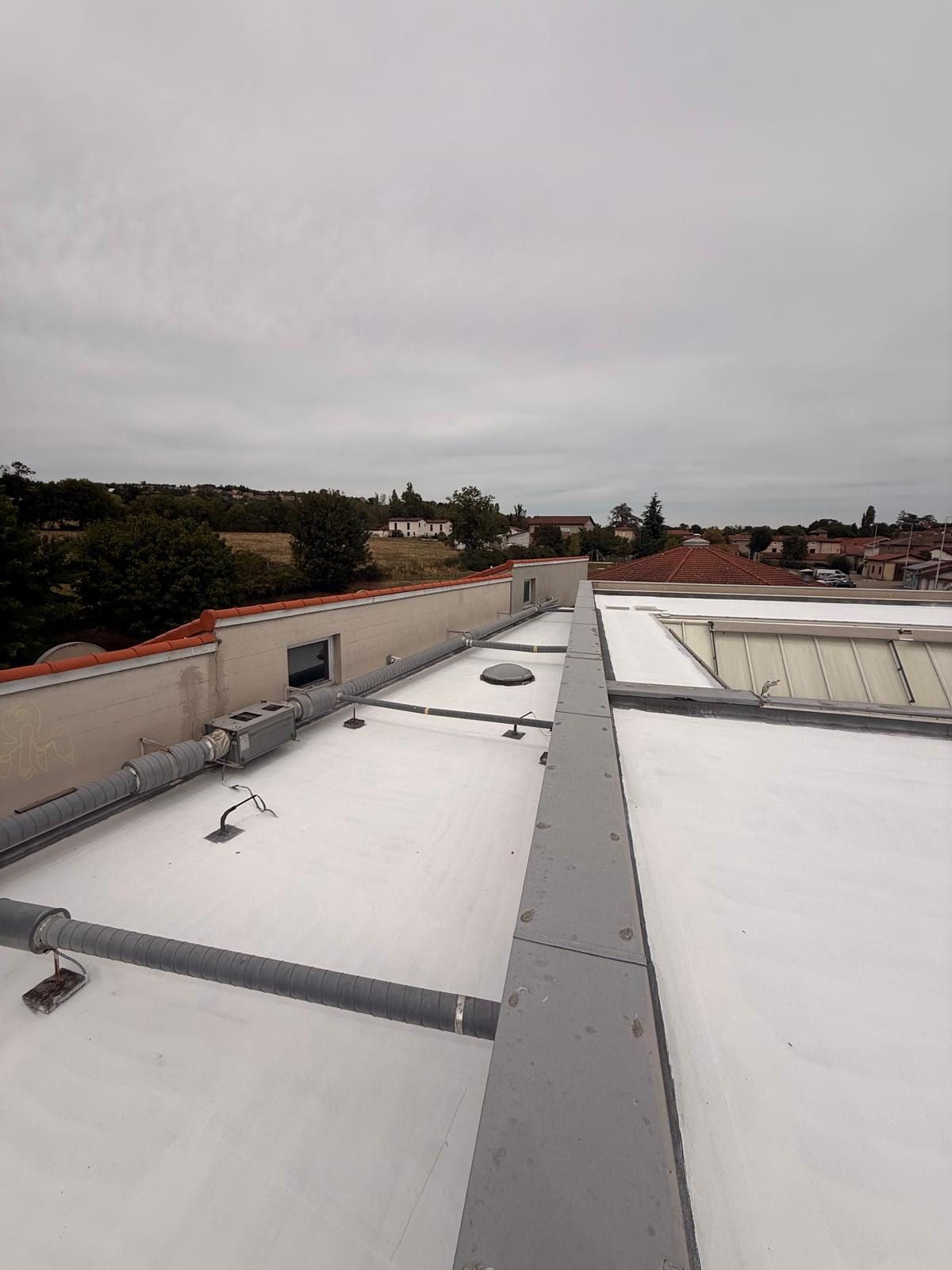 Flat roofs of the school coated white, school buildings and village