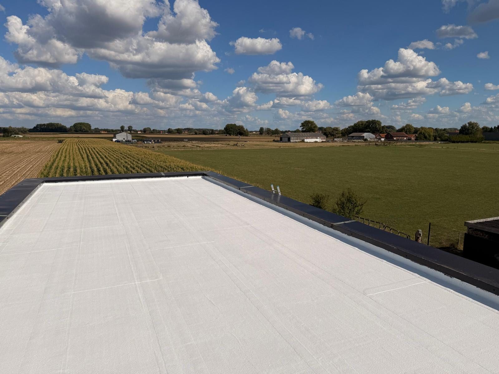 Flat roof of a house near Lille treated as a cool roof, fields in the background