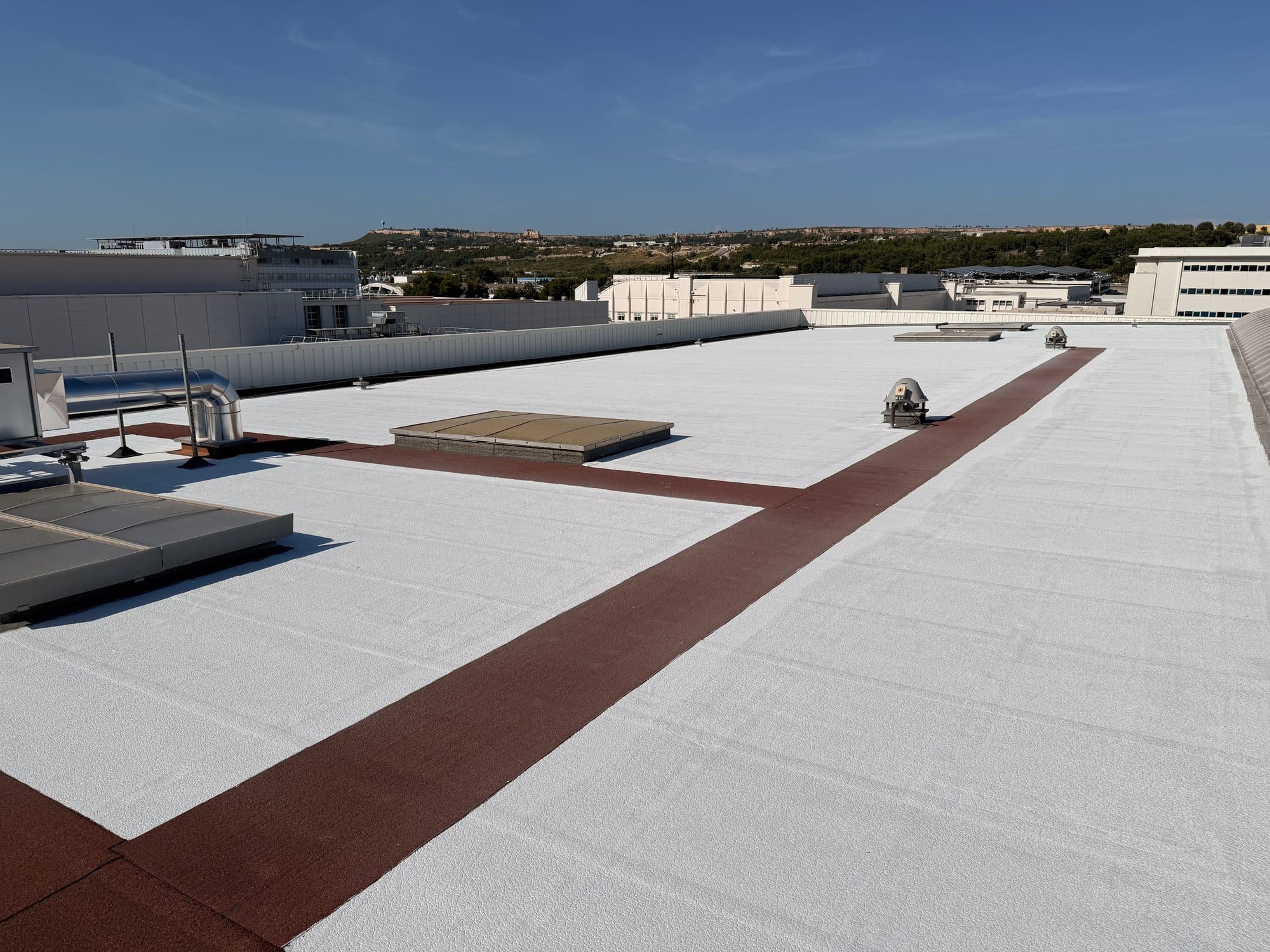 Toiture du plus grand bâtiment d’Airbus Marignane après application du cool roof PrimaTherm®, pistes de l’aéroport en arrière-plan